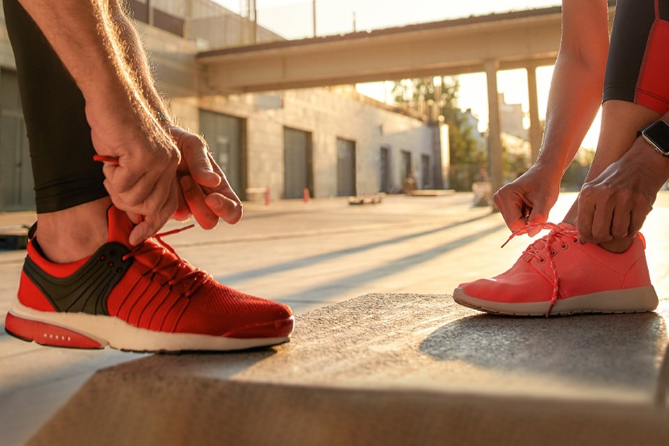 A man and a woman tie up their trainers before jogging.